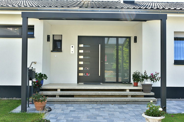Dunkle Haustür mit mehreren Glaselementen in einer hellen Fassade