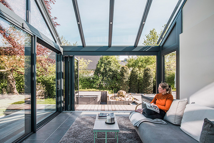 Ein gutes Buch, eine gemütliche Couch und der Blick in den Garten: An lauen Herbsttagen lässt sich die Natur im geschützten, aber offenen Wintergarten ganz entspannt genießen.