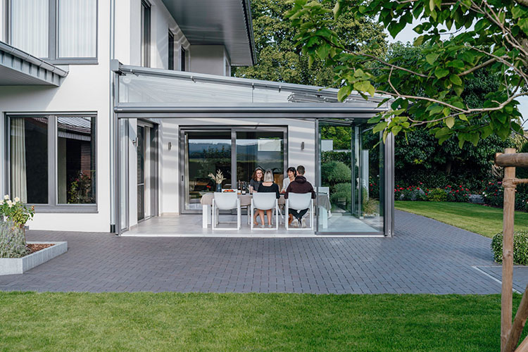 Platz für die ganze Familie: Im Outdoor-Wohnzimmer essen alle gemeinsam in großer Runde, umrandet vom grünen Garten.