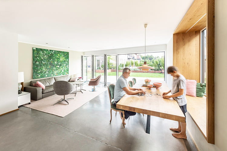 Jens Hermann und sein Sohn Tim genießen die Helligkeit und frische Luft im Wohnbereich beim gemeinsamen Puzzeln.