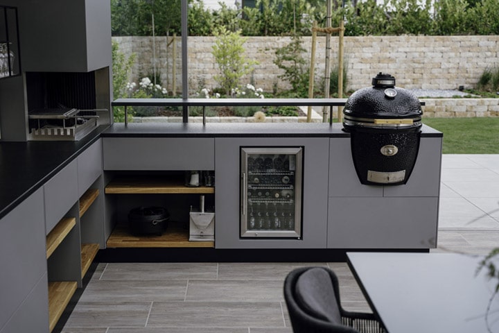 Die Outdoorküche bietet neben einem Kugelgrill, einem Grillkamin sowie einem kleinen Kühlschrank viel Platz für Teller, Grillzubehör & Co.