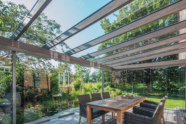 Alles aufeinander abgestimmt: Mit Holzboden, Möbeln aus natürlichen Materialen und den innenliegenden Holzprofilen fügt sich das Glashaus perfekt in den Garten ein.