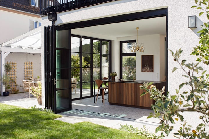 Die Glas-Faltwand von Solarlux öffnet die Fassade vollständig und schafft einen barrierefreien Übergang zum Garten.
