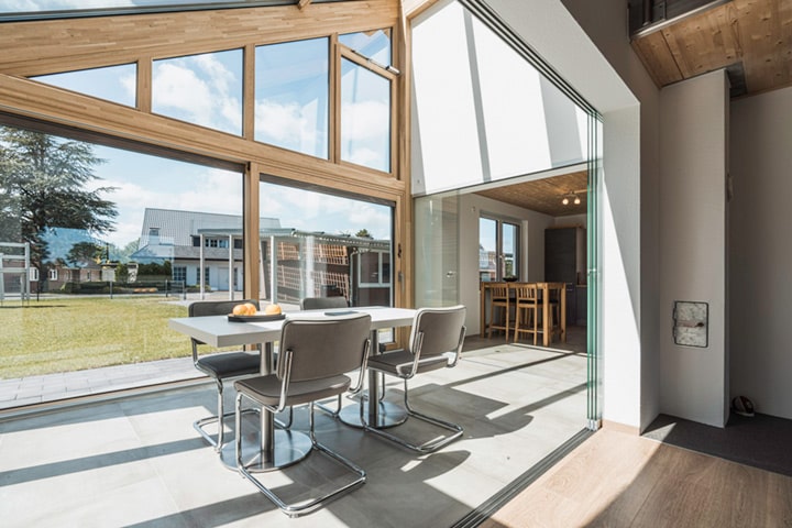 Küche und Wohnzimmer lassen sich bei Bedarf mit gläsernen Schiebeelementen trennen. Geschlossen stehen die Elemente bündig an der Wand und wirken nahezu unsichtbar.