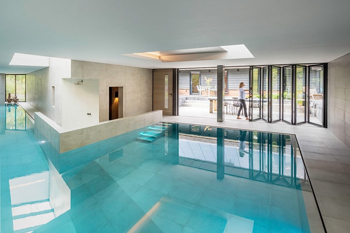 Obwohl der Wellnessbereich im Hügel eingebettet ist, ist das Schwimmbad lichtdurchflutet. Die Glas-Faltwand ist hier der Hauptakteur.