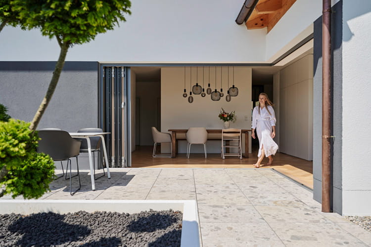 Die Glas-Faltwand öffnet den Innenraum großzügig zur Terrasse und schafft eine harmonische Verbindung zwischen Haus und Garten.