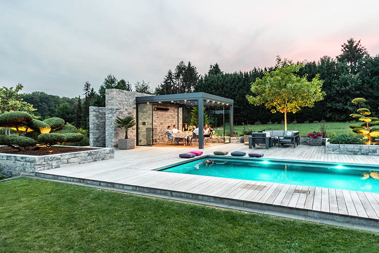 Der Pool samt gläsernem Poolhaus fügt sich harmonisch in die Gartengestaltung ein und wird so Teil des Lebensraums.