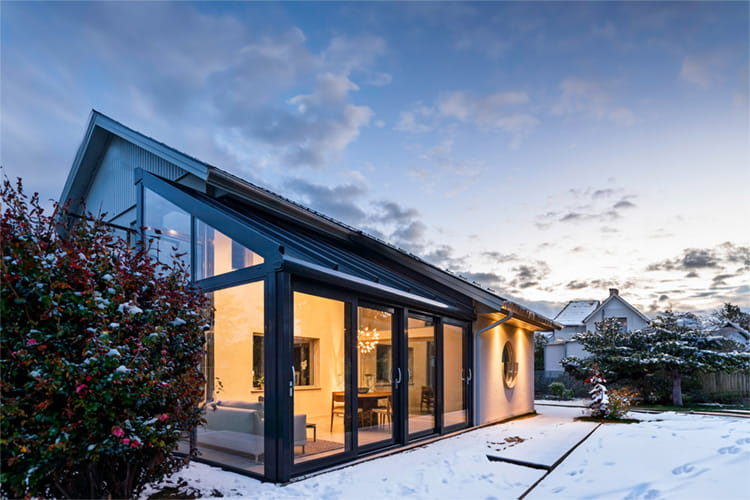 In der blauen Stunde entfaltet der gläserne Anbau seine ganze Eleganz – Licht, Architektur und Natur im perfekten Zusammenspiel.